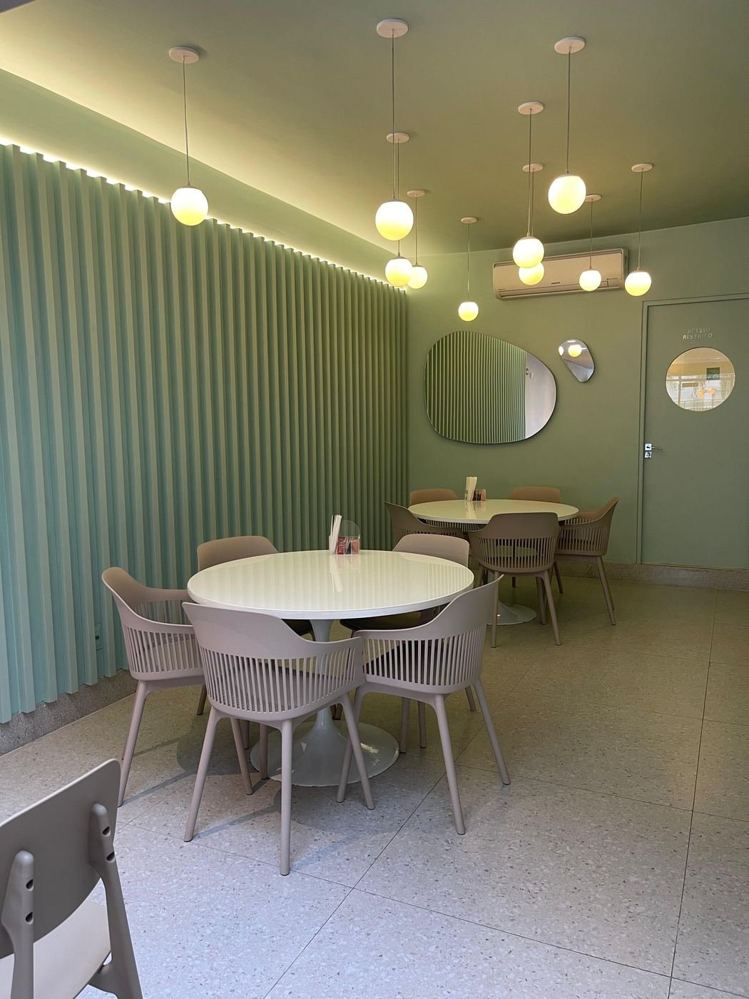 Salão verde com mesas redondas e luminárias
